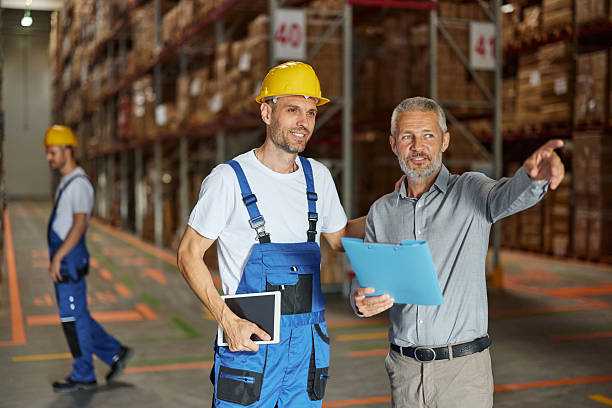 istock Happy mature inspector giving instructions to his worker in storage room. 2217098711