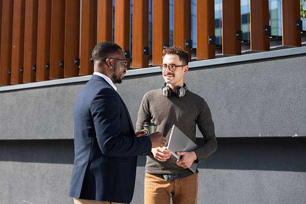 istock Two colleagues having a casual conversation outside a modern building on a sunny day 2217099943