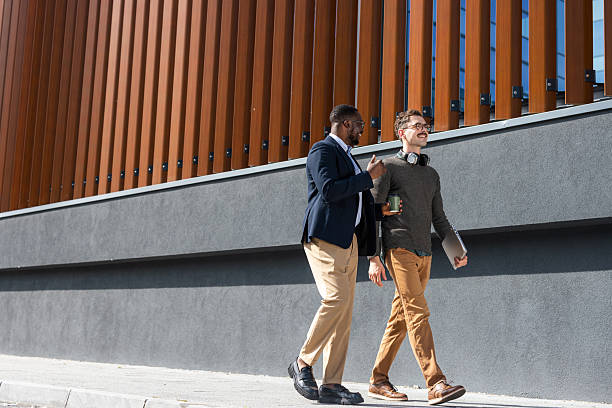 istock Two colleagues are walking outside an urban building, discussing work 2217099946