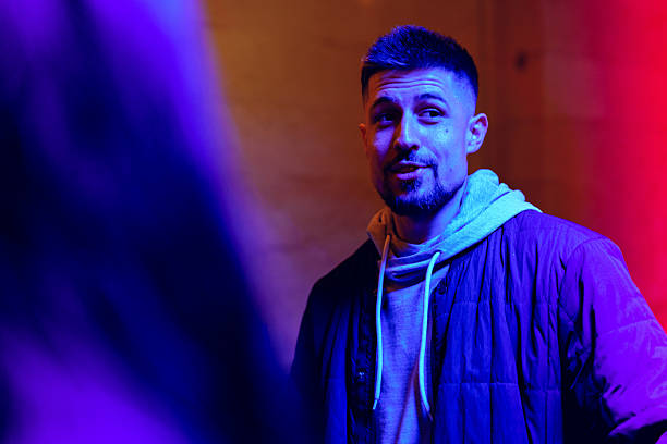 istock Young man engaging in conversation under colorful lights in an urban setting during night hours 2217102984