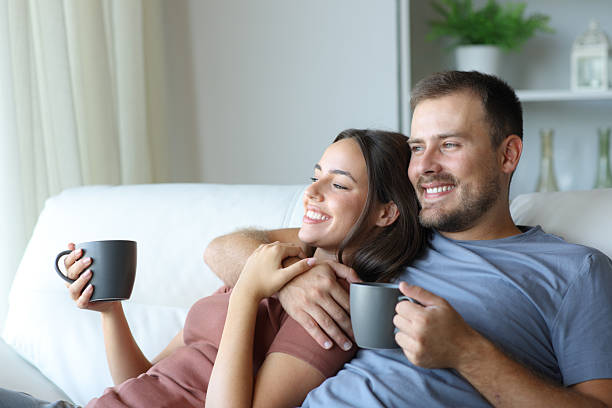 istock Happy couple drinking tea looking away in a house interior 2217104936