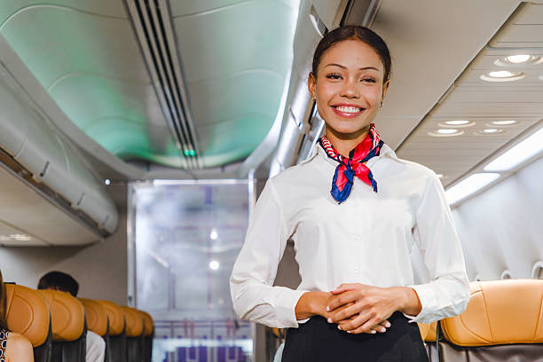 istock Smiling flight attendant standing in airplane aisle, offering in-flight service. Represents hospitality, airline safety, and passenger care aboard commercial flights. Ideal for travel industry visuals 2217107773