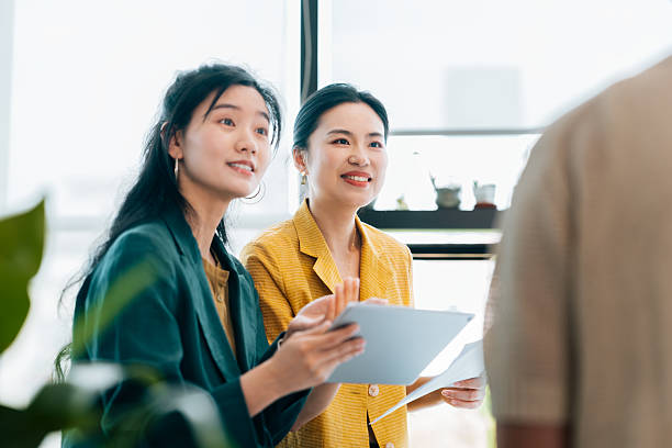 istock Portrait of two confident young Asian businesswomen using digital and checking documents during the meeting. Discussing strategy, the company mission and vision for the future. 2217108106