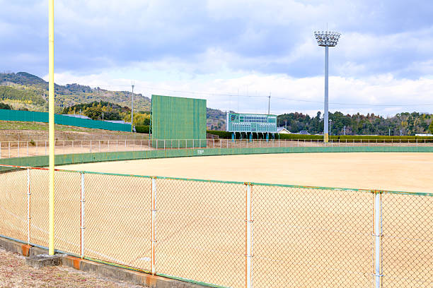 Baseball stadium full of fans in the stands with copy space. Deliberate focus on foreground infield dirt clay with shallow depth of field on background. Floodlights flare for effect and copy space. Fictitious stadium created in Photoshop.