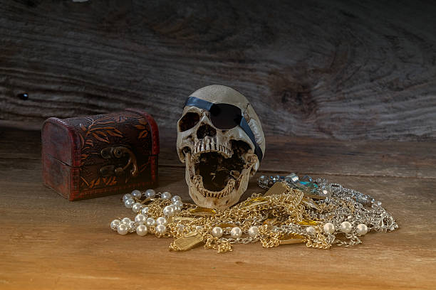 istock The pirate skull with treasure on wooden background. 2217108971