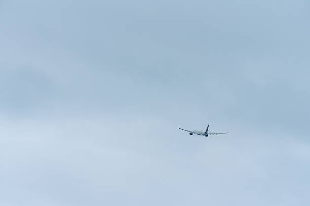 White passenger airplane flying over barcelona airport in el prat de llobregat, catalonia, spain