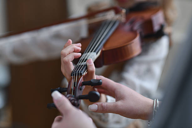 istock Attentive Teacher Supporting Violin Student By Adjusting Her Hand While She is Playing 2217112780