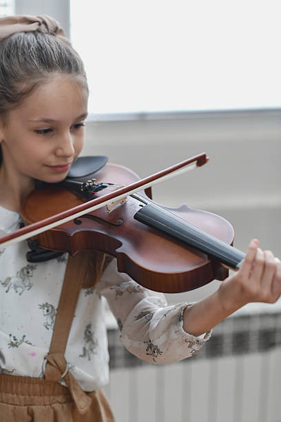 istock Beautiful Girl Looking Happy and Fulfilled While Playing Violin With Focus 2217113445