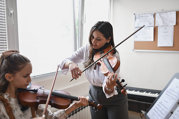 istock Young Student Enjoying Class While Playing Violin Together With Female Professor 2217114185