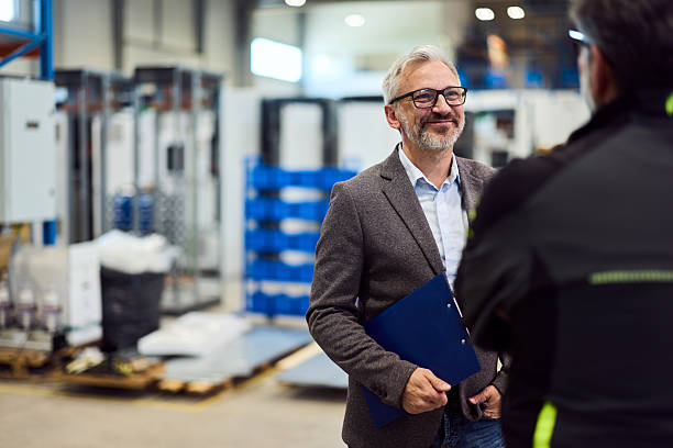 Businessman Having a Friendly Conversation in a Manufacturing Facility stock photo