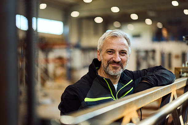Smiling Senior Man in Industrial Setting with Positive Expressions stock photo