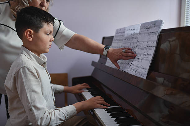 istock Female Teacher Pointing At Difficult Passage While Boy is Playing Piano With Full Focus 2217115093