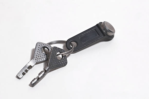 istock Two silver metal keys attached to black electronic key fob on white surface symbolizing access and security 2217115540