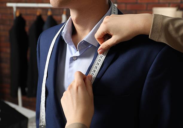 istock Professional tailor measuring jacket lapel on client in atelier, closeup 2217117240