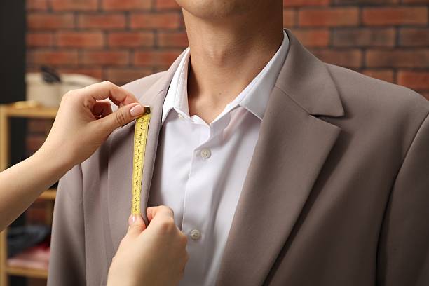 istock Professional tailor measuring jacket lapel on client in atelier, closeup 2217117245