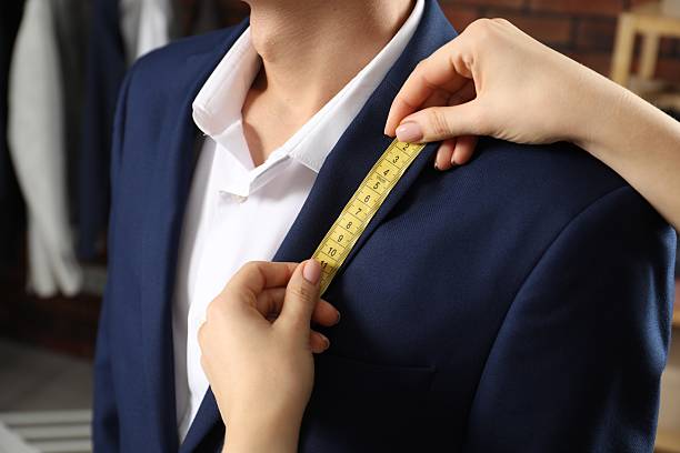 istock Professional tailor measuring jacket lapel on client in atelier, closeup 2217117261