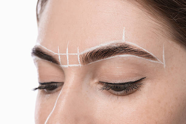 istock Young woman during henna eyebrows dyeing procedure on light background, closeup 2217119586