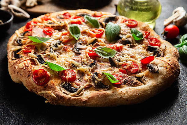 istock Appetizing pizza with ham, tomatoes and cheese close-up. Thin pizza 2217121344