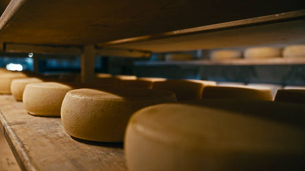 istock Aging Cheese Wheels Arranged on Rustic Wooden Shelving 2217122991