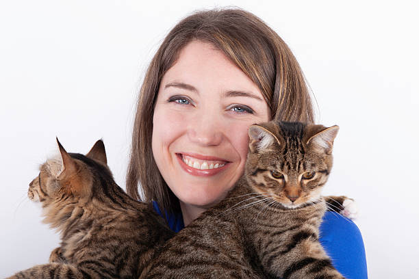 istock Attractive young woman holding two cats against white background. 2217125865
