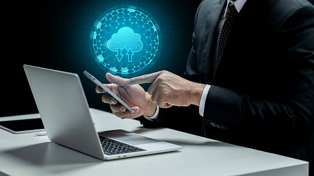 istock Businessman touching cellphone with cloud computing icon. Laptop and tablet on the desk. Technology innovation on the virtual screen. Concept of a Data Center 2217127112