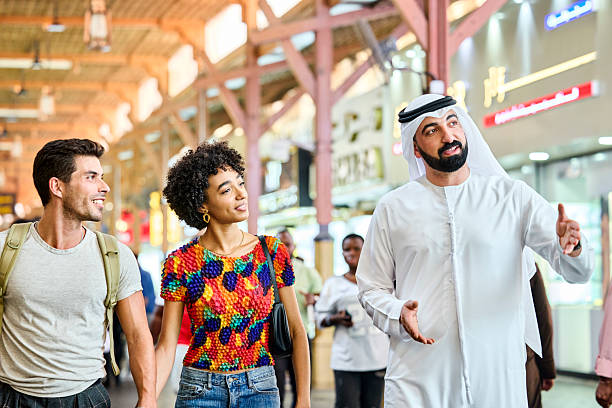 Local Saudi guide educating tourists walking at street. Couple are learning about traditions and cultures. They are holding hands.