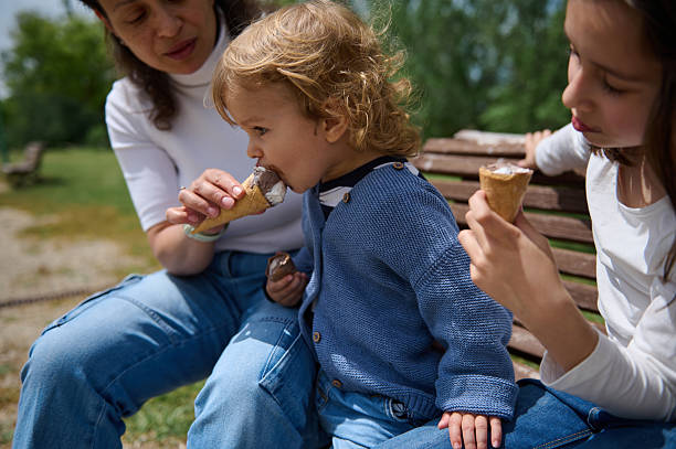 istock Family Enjoying Ice Cream Together Outdoors in a Park Setting 2217131578