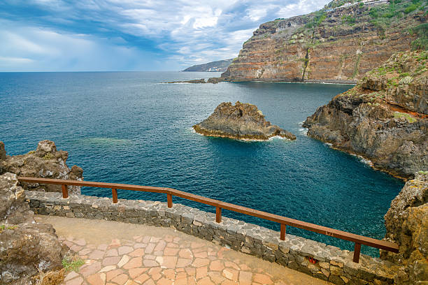 Stunning coastal viewpoint with wooden railing overlooking dramatic cliffs and turquoise ocean waters in Tenerife El Sauzal, Spain