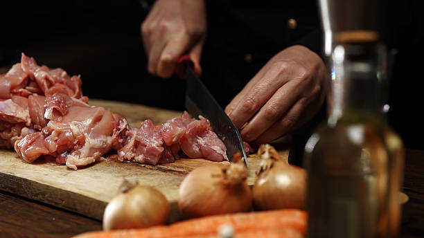 istock Female Chef Cutting Chicken Thighs with Knife. 2217134382
