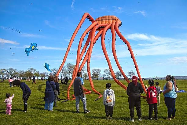 Milwaukee, Wisconsin, USA – May 24, 2025: A large orange sea creature kite floats near a small group of kids and adults at the 2025 IKEA Kite Festival on Milwaukee’s Lakefront.