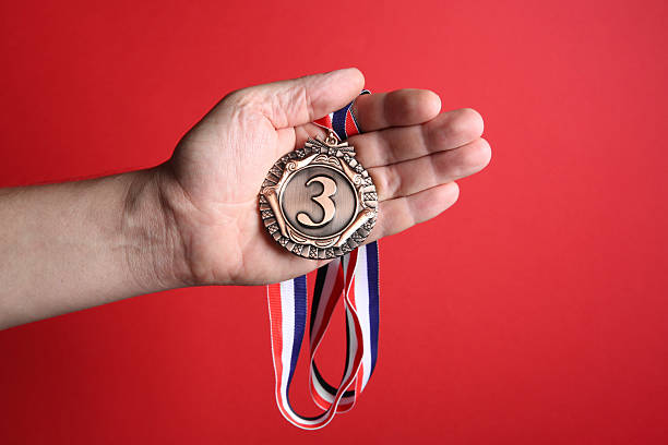 istock Man with bronze medal on red background, closeup 2217143629