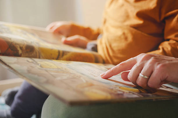 Mother's finger points to a page in a book while explaining a story to her child.