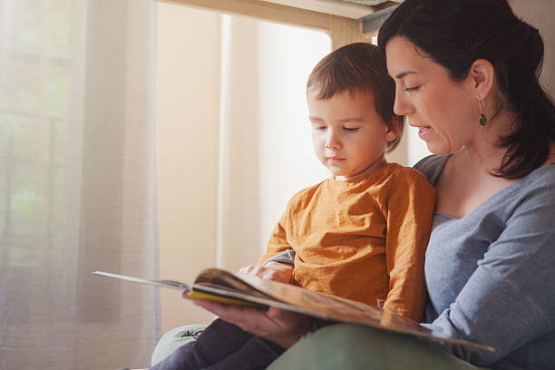istock Toddler and mother share book on bed in natural light 2217143711