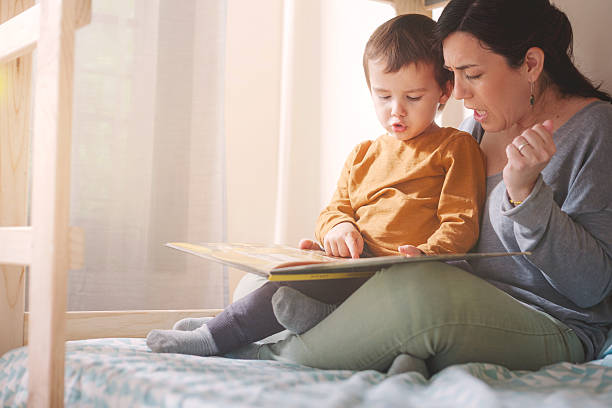 istock Mother and toddler reading together in bed with soft daylight 2217143734