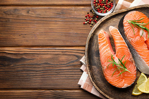 istock Fresh raw salmon steaks and spices on wooden table, flat lay. Space for text 2217145413