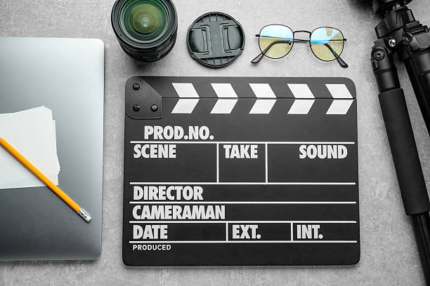 istock Flat lay composition with movie clapper, camera lens and laptop on grey textured table 2217145857