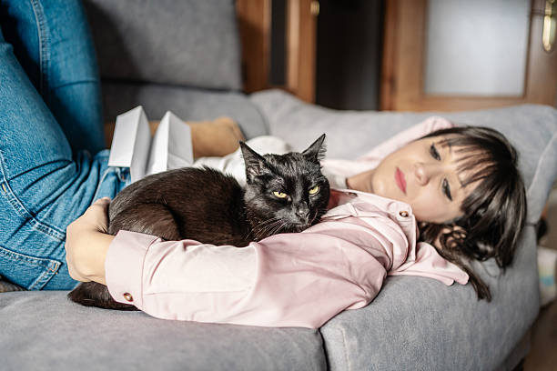istock Woman relaxing on sofa with black cat embracing comfort and affection 2217147281