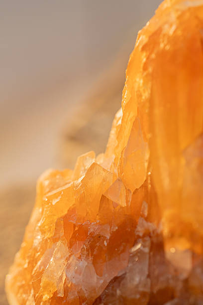 Vertical macro view of a golden citrine mineral with detailed crystalline structure and warm lighting that accentuates the orange hues and transparency.