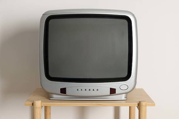 istock Retro tv set on wooden shelf against white wall 2217150802