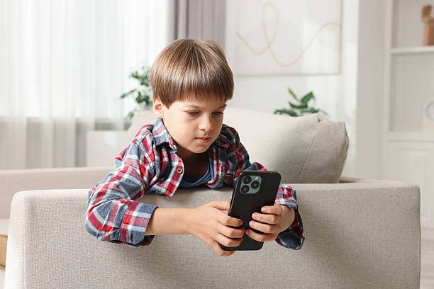 istock Cute little boy using smartphone on sofa at home 2217151470