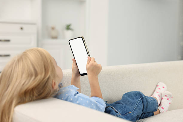 istock Cute little girl using smartphone on sofa at home 2217151697