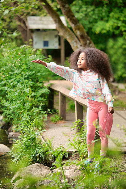 Pastel-clothed little girl helping wildlife by feeding water birds.