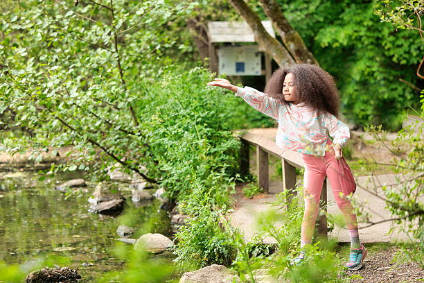 Pastel-clothed little girl helping wildlife by feeding water birds.