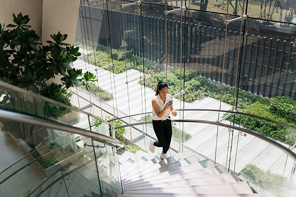 istock Businesswoman walking down stairs while using smartphone and drinking coffee 2217157749