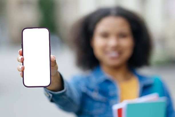 istock Smiling Young Black Female Student Demonstrating Blank Smartphone Screen While Standing Outdoors 2217158042