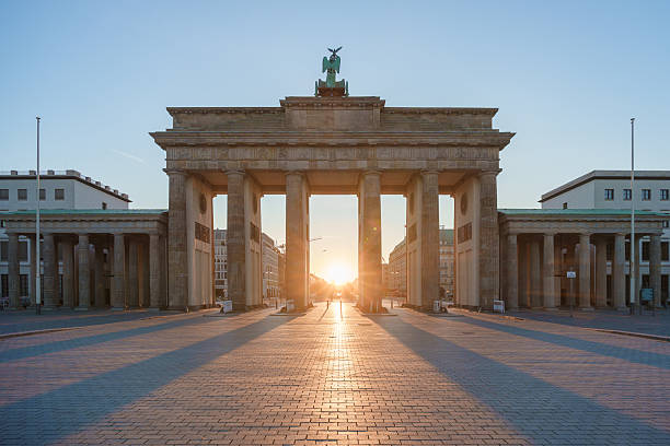 istock The Brandenburg Gate in Berlin at sunrise, casting long shadows on the empty square with soft golden light illuminating the historic monument 2217162011