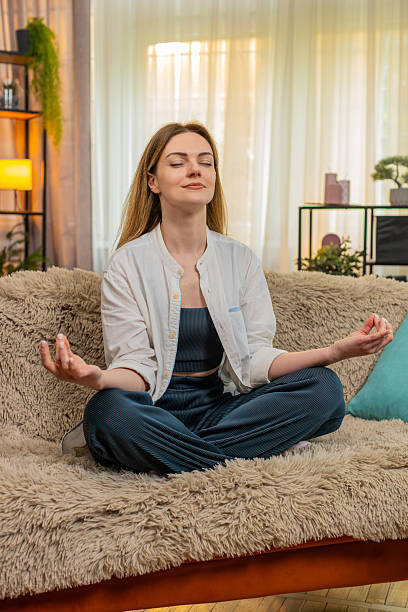 istock Woman meditating peacefully on home sofa, calm expression, eyes closed, relaxation, taking a break 2217163534