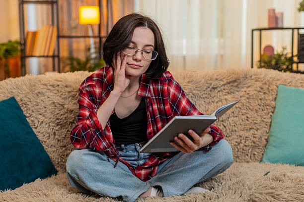 istock Young woman reading old journal notebook at home, smiling thoughtfully with soft nostalgic emotion 2217163585