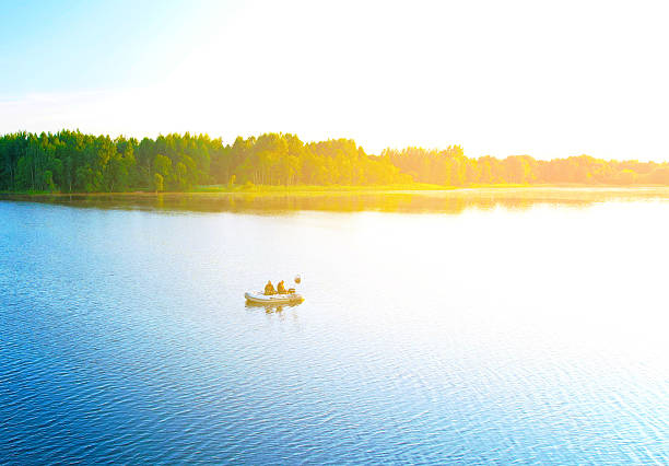 Fishermen boat on lake, drone view. Fishing for river fish from a motor boat use a fishing rod, spinning rod. Fishing boat with a fisherman on lake while catching fish, aerial view.