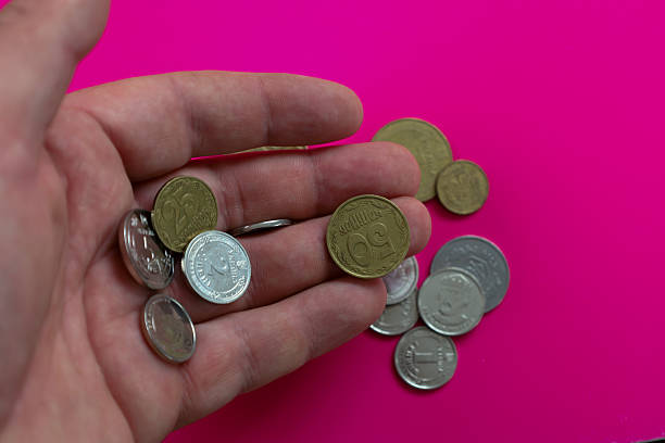 A person's hand holds a handful of various coins, symbolizing accumulation or preparation for payment. This image is ideal for visualizing everyday financial transactions, budgeting, and savings. It reflects the concept of money circulation and personal finance.